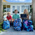 Three kids ready for school with First Aid Kits hanging from their backpacks   